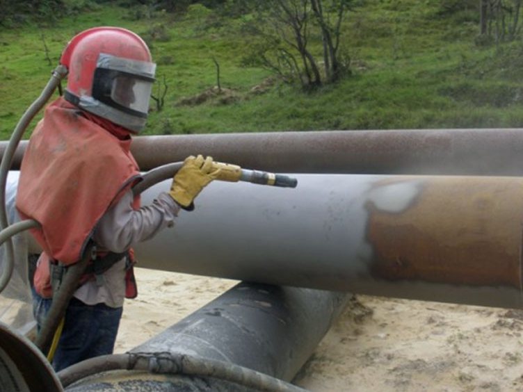 пескоструйная обработка стальной трубы в кабине цеха